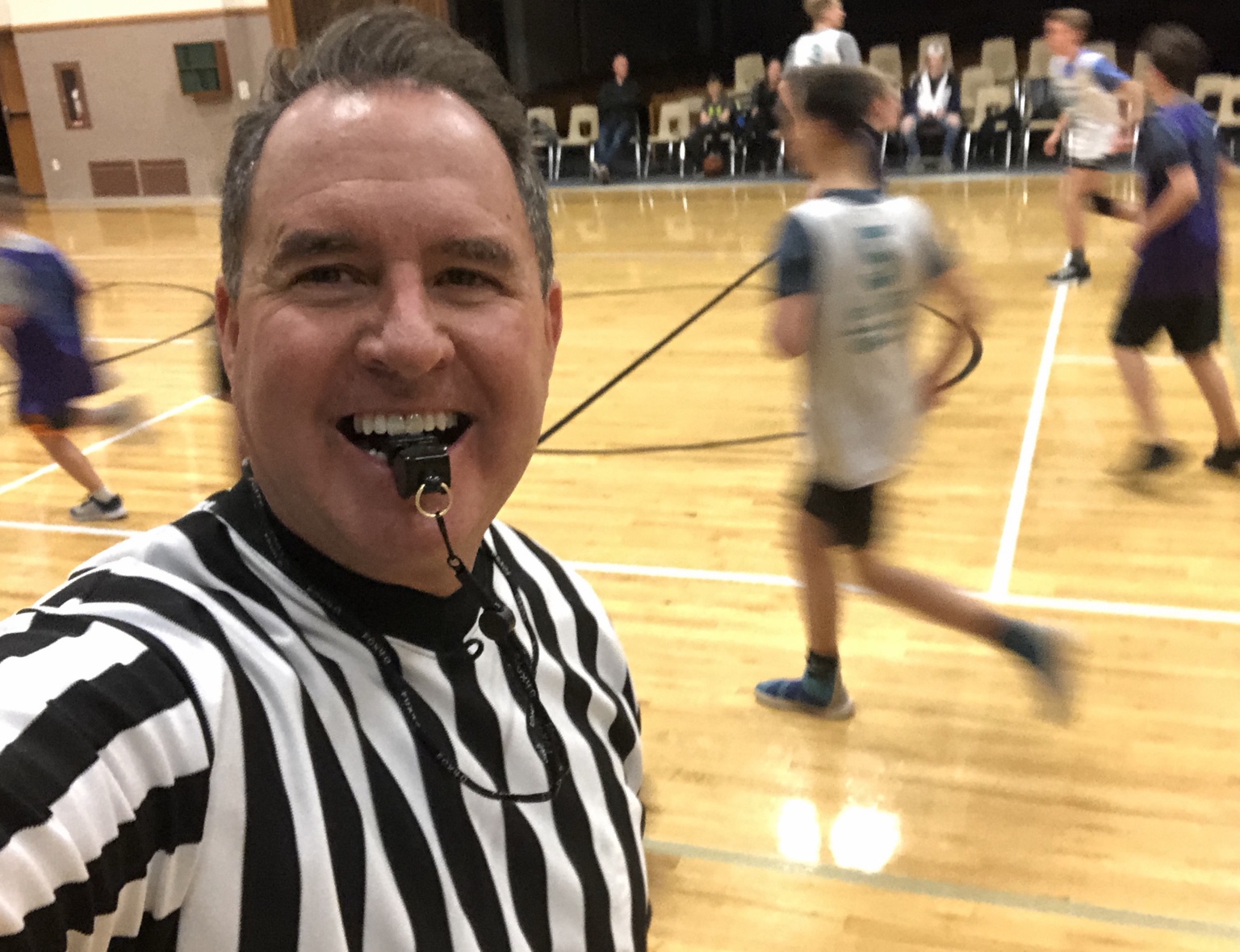 Jeff smiling with a whistle while refereeing basketball
