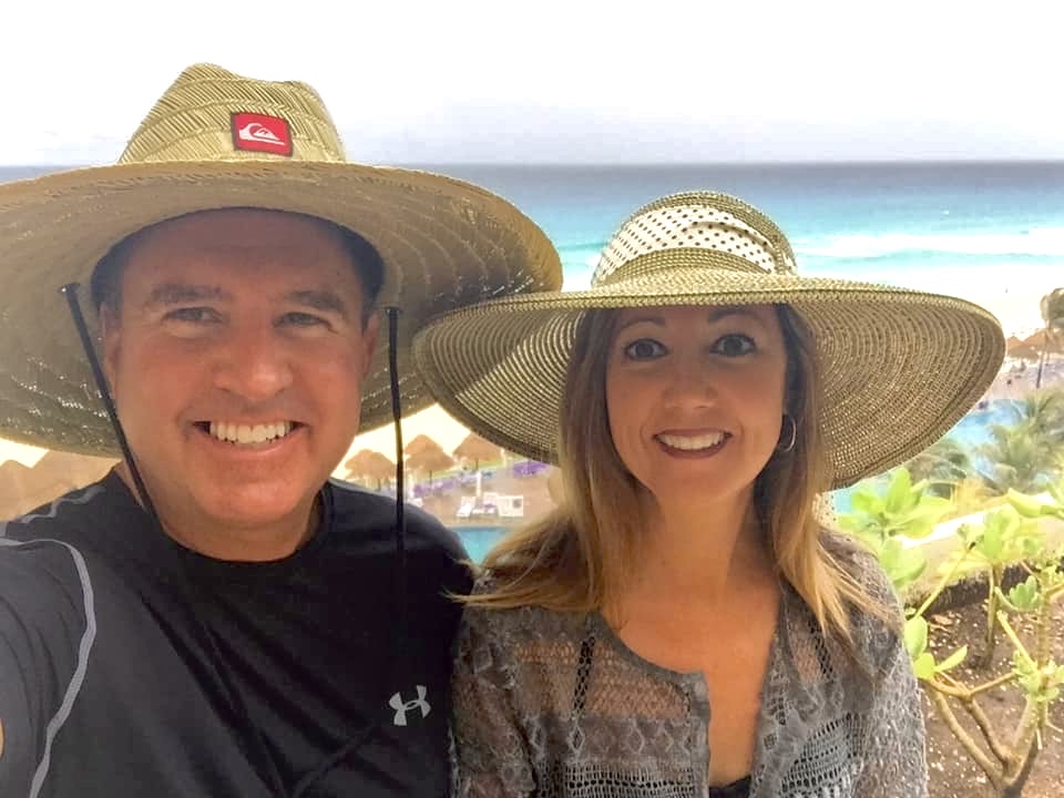 Jeff and a companion smiling in straw hats at the beach