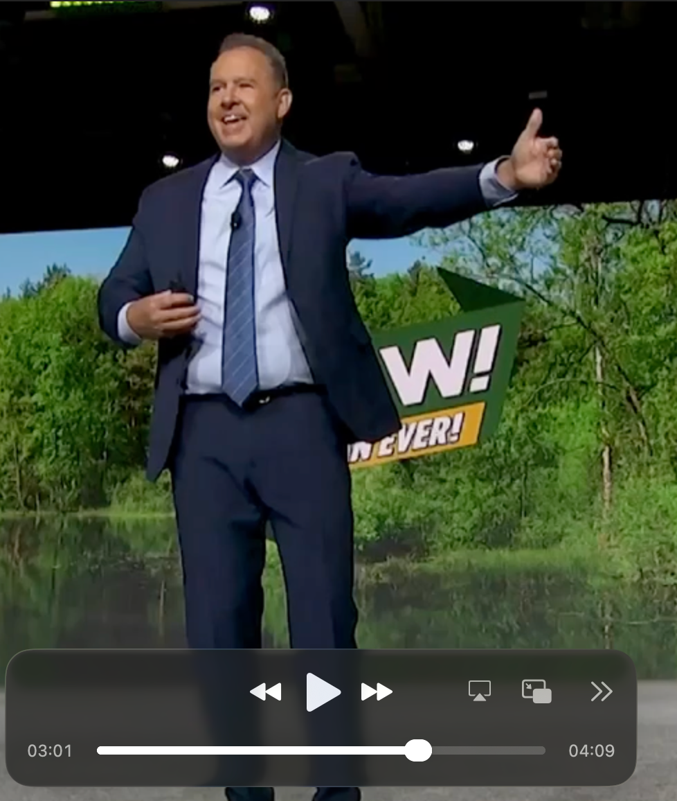 Jeff smiling and extending an arm toward the room during a keynote