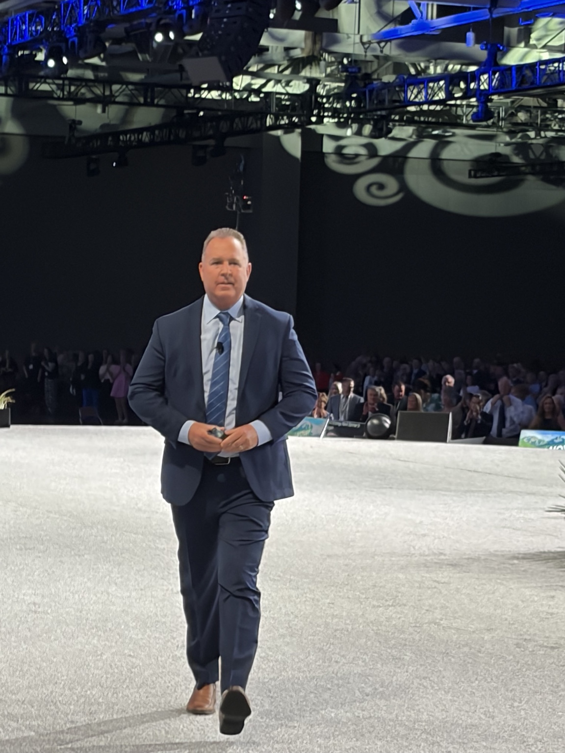 Jeff walking on stage with an audience behind him