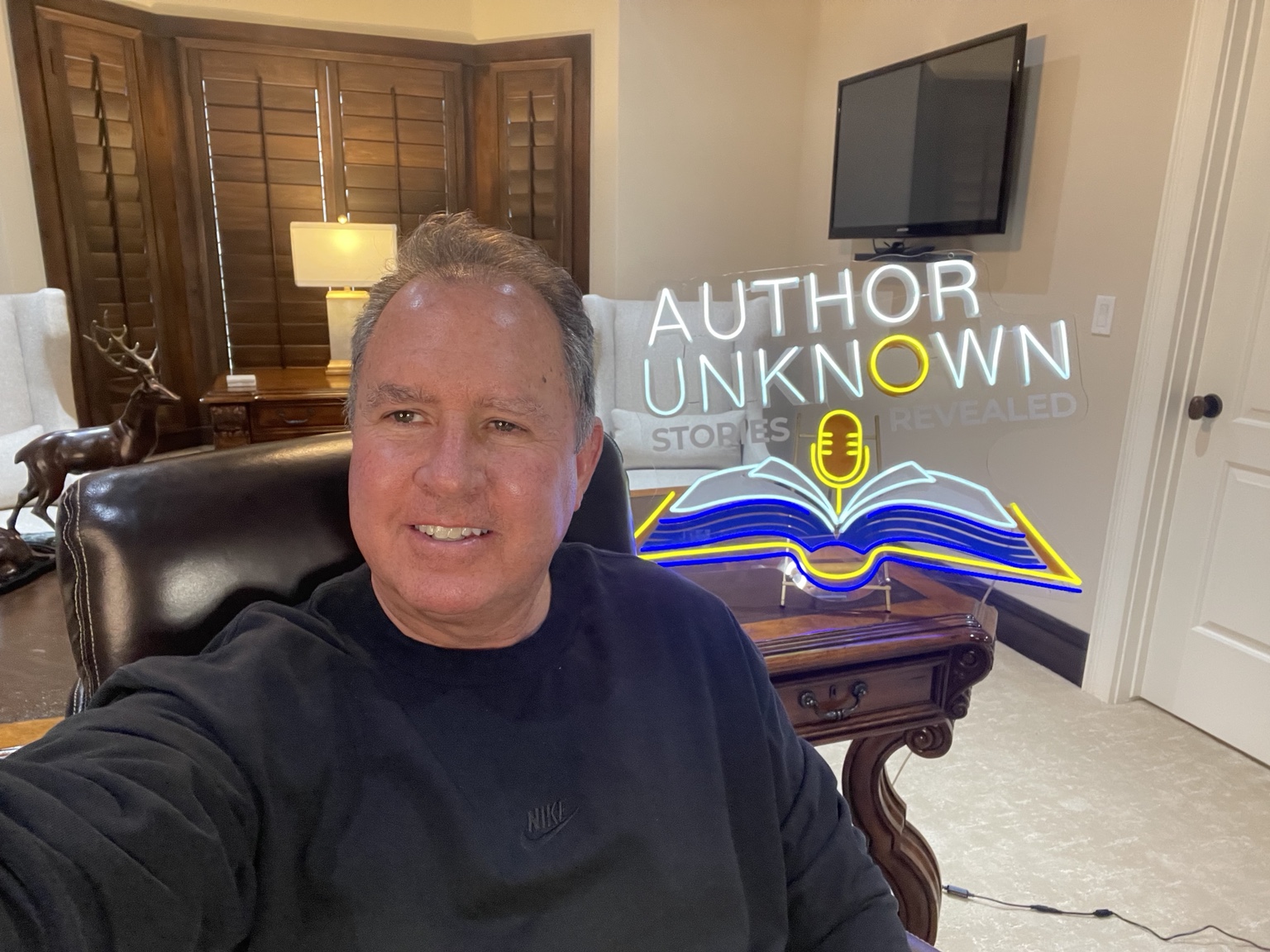 Jeff smiling beside the illuminated Author Unknown sign