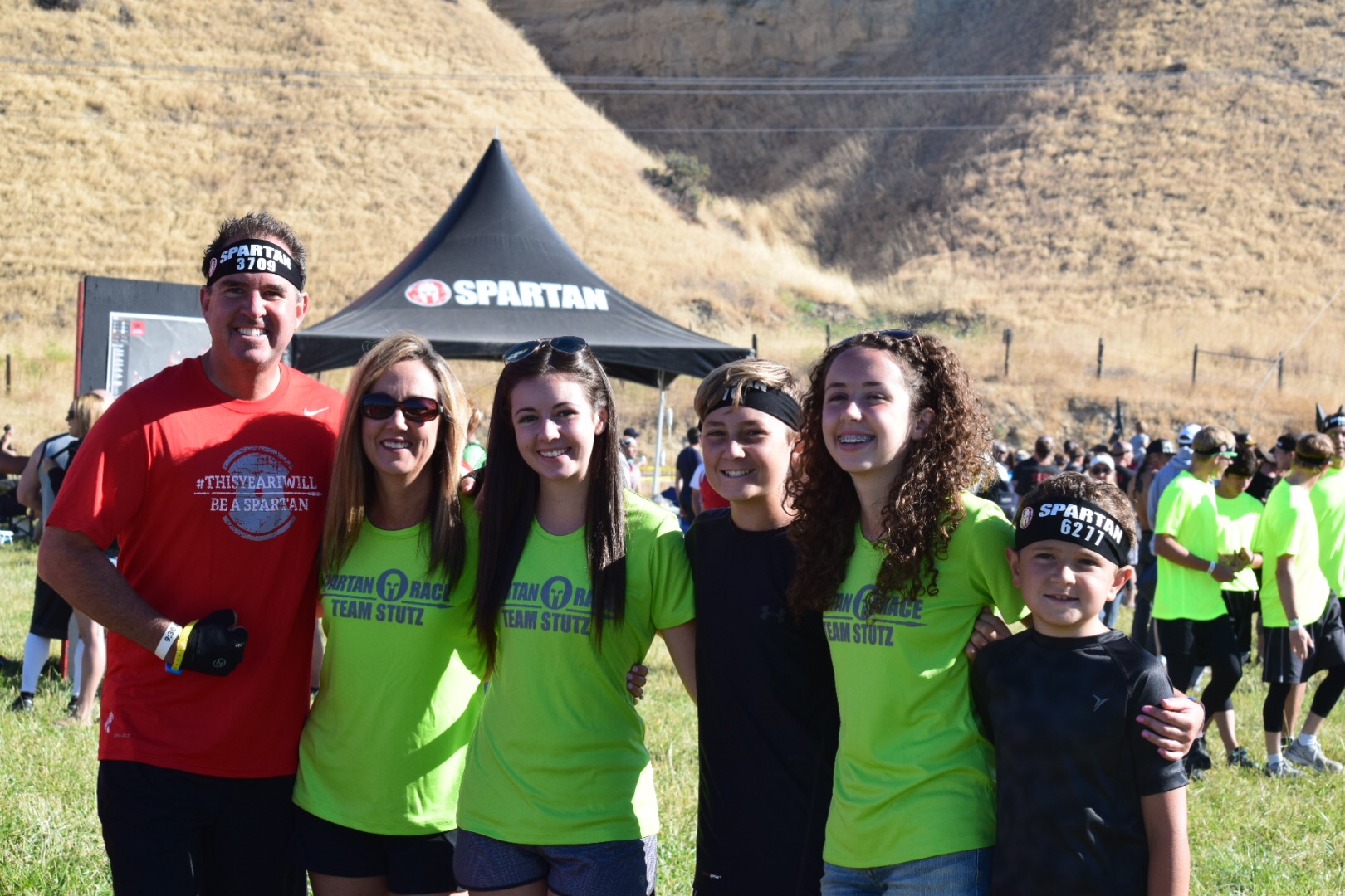 Jeff and his family smiling together at a Spartan race in Team Stutz shirts