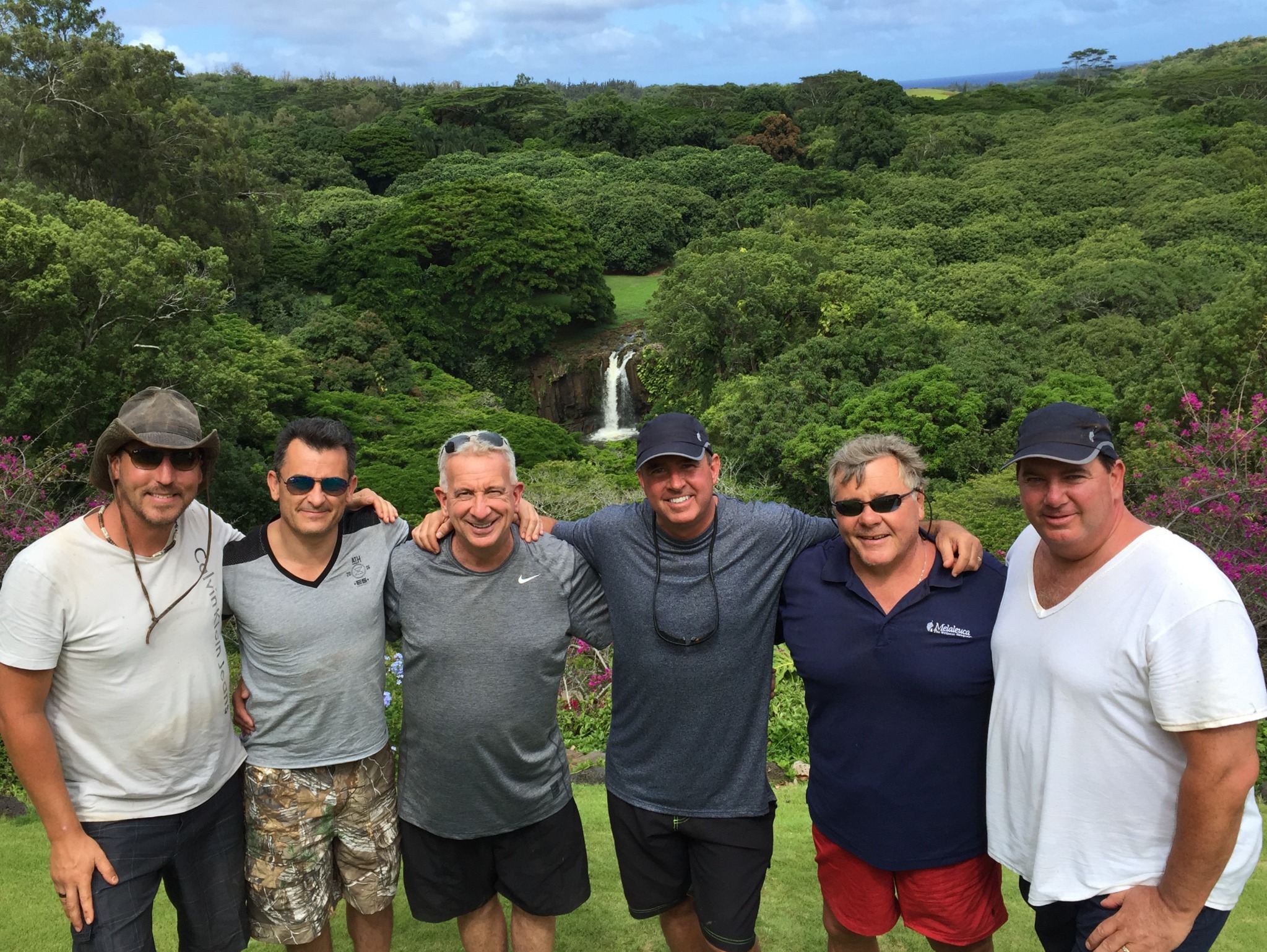 Jeff and friends smiling together at a lush waterfall overlook